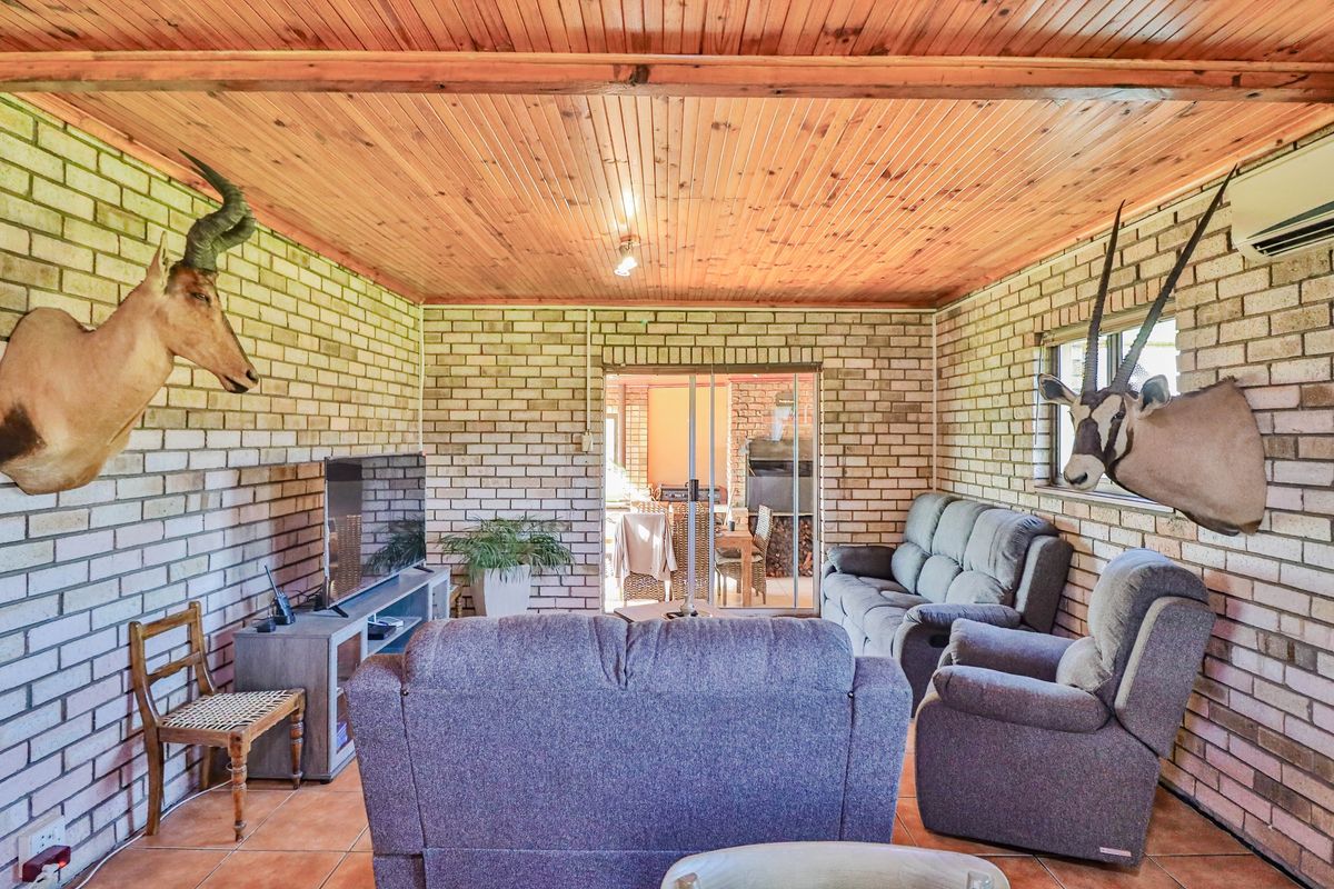 A rustic living room featuring exposed brick walls, a timber-clad ceiling, and sliding glass doors leading to an outdoor patio area.