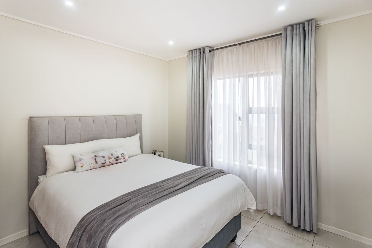 A well-maintained bedroom featuring neutral walls, tiled flooring, and recessed downlighting, creating a bright and comfortable living space.