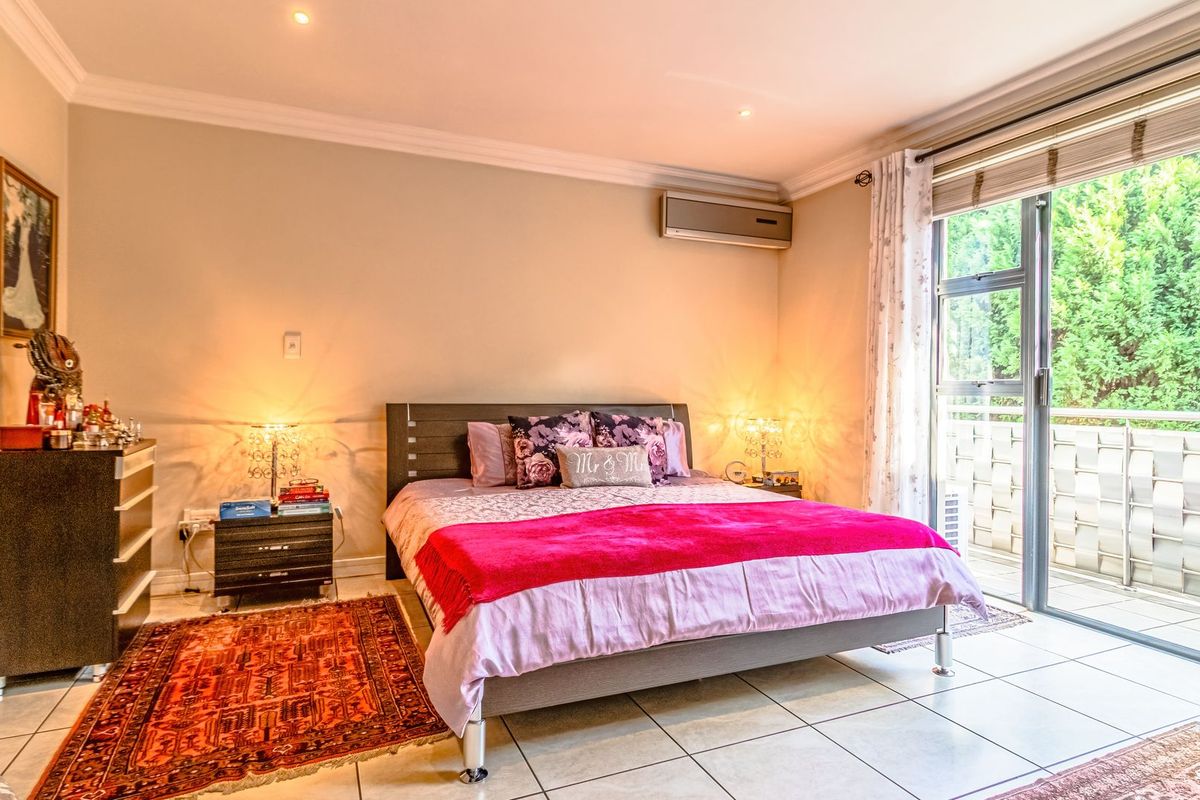 Spacious bedroom featuring tiled flooring, a wall-mounted air conditioning unit, and large sliding glass doors providing direct access to a private balcony.
