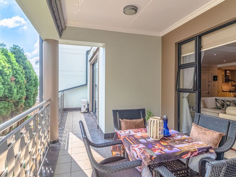 A covered balcony featuring tiled flooring, a stainless steel balustrade, and direct access to the interior living area through sliding glass doors.
