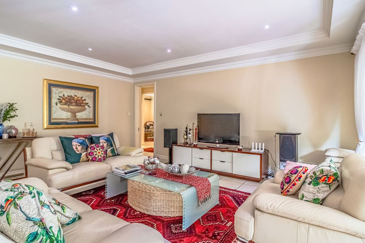 A well-maintained living room featuring recessed downlighting, coved ceiling details, and large sliding glass doors providing access to the exterior.