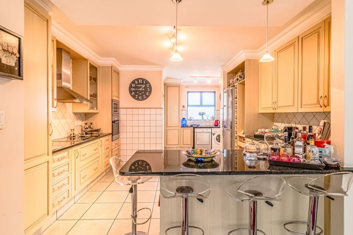A well-appointed kitchen featuring granite countertops, ample built-in cabinetry, a central island, and tiled flooring, offering a functional and organized cooking space.
