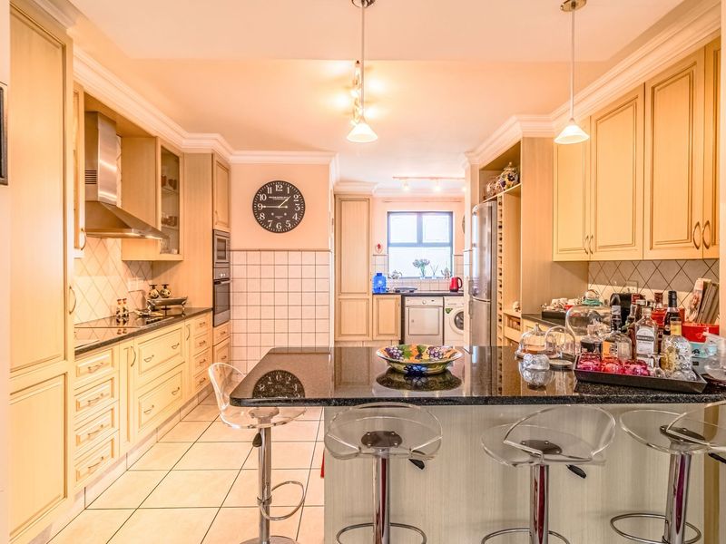 A well-appointed kitchen featuring granite countertops, ample built-in cabinetry, a central island, and tiled flooring, offering a functional and organized cooking space.