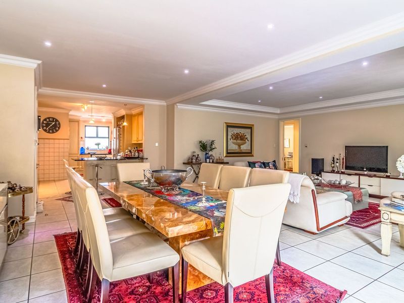 Spacious open-plan living and dining area featuring tiled floors, recessed lighting, and a connected kitchen with island seating.