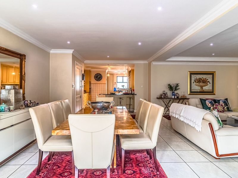 Spacious open-plan living and dining area featuring tiled floors, recessed lighting, crown molding, and a seamless transition to the kitchen with a breakfast bar.