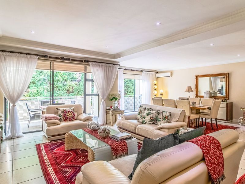 Spacious open-plan living and dining area featuring tiled floors, recessed ceiling lighting, and large sliding glass doors leading to an outdoor balcony.