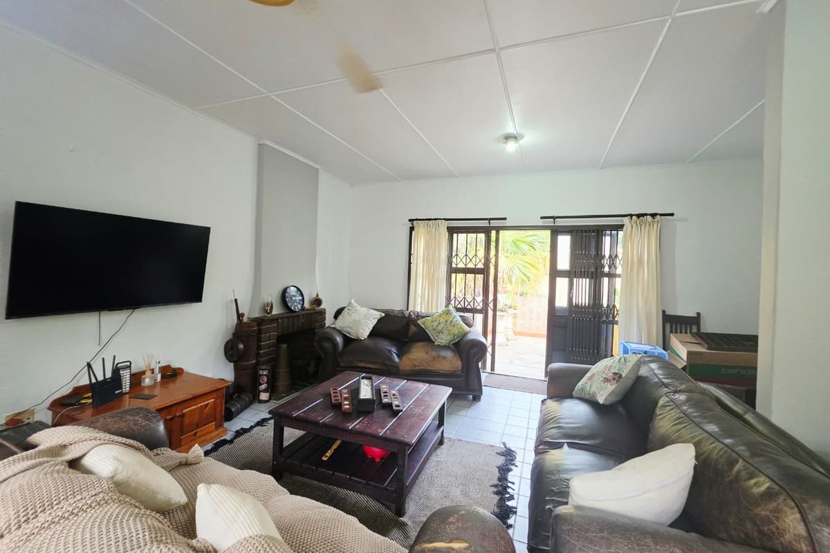 Spacious living room featuring a brick fireplace, tiled flooring, and direct access to the outdoor area through a security gate.