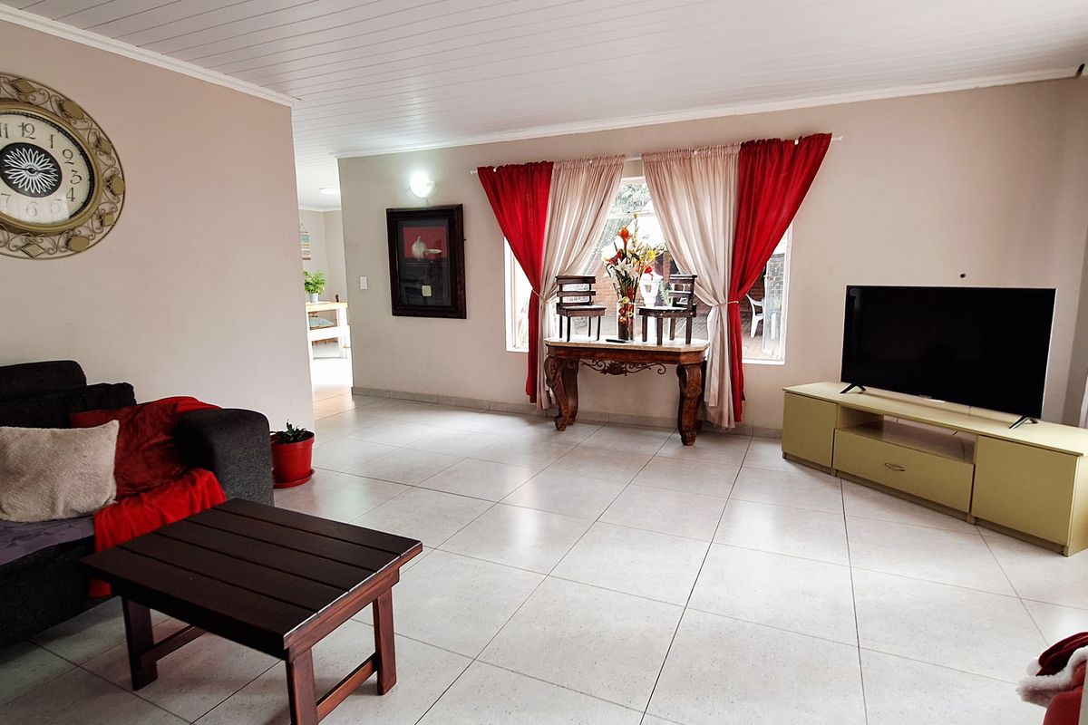 Spacious living room featuring large format floor tiles and a white tongue-and-groove ceiling, offering a bright and open layout.