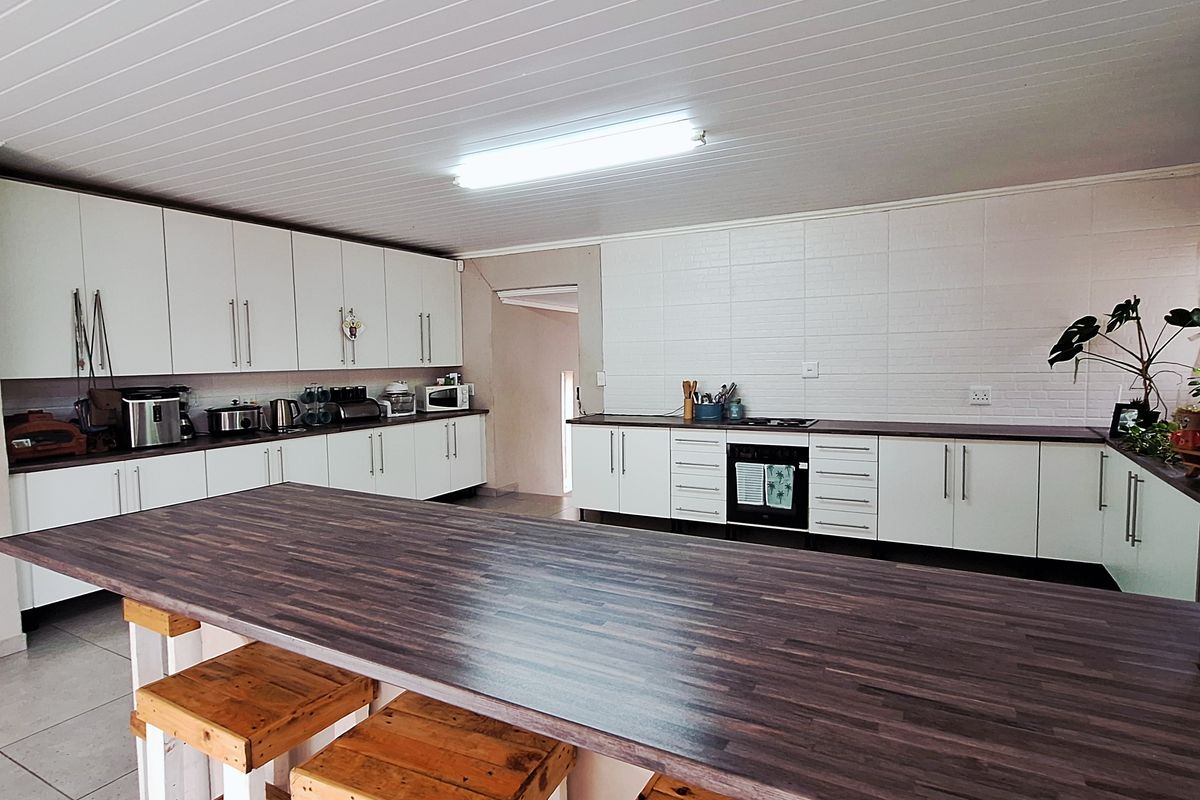 Spacious kitchen featuring white cabinetry, dark wood-look countertops, a large central island, and a tiled floor.