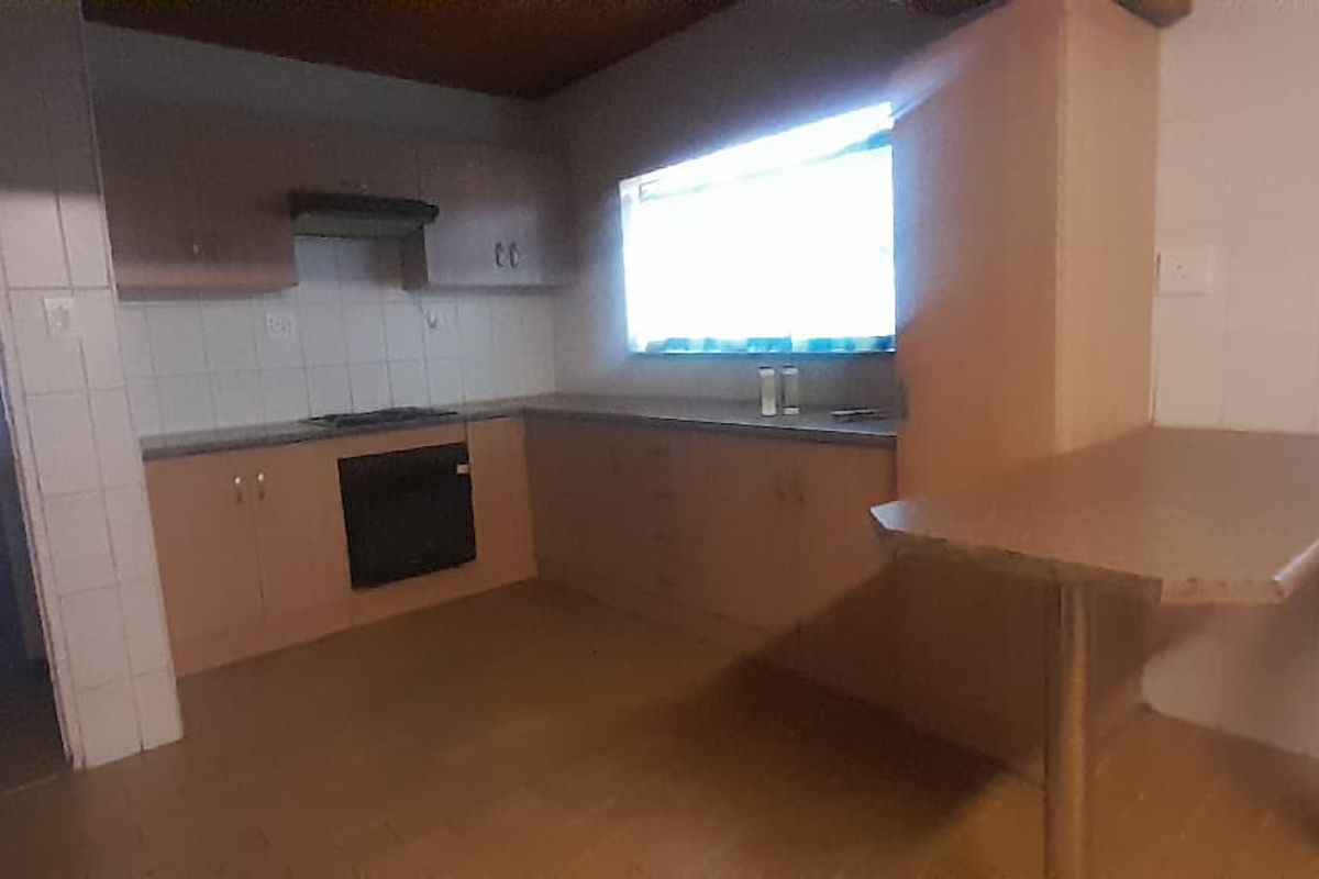 A dated kitchen featuring built-in cabinetry, a hob, oven, and extractor fan, offering a functional layout ready for modern renovation.