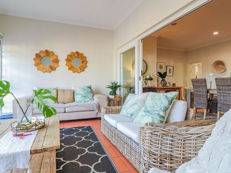 A bright, enclosed patio area featuring terracotta floor tiles and large sliding glass doors that connect seamlessly to the interior dining space.