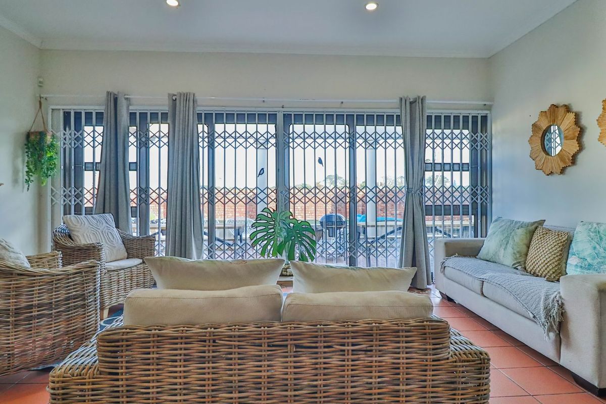 A comfortable living room featuring tiled flooring and large sliding glass doors secured with metal security gates, providing direct access to the outdoor area.