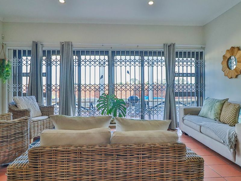 A comfortable living room featuring tiled flooring and large sliding glass doors secured with metal security gates, providing direct access to the outdoor area.