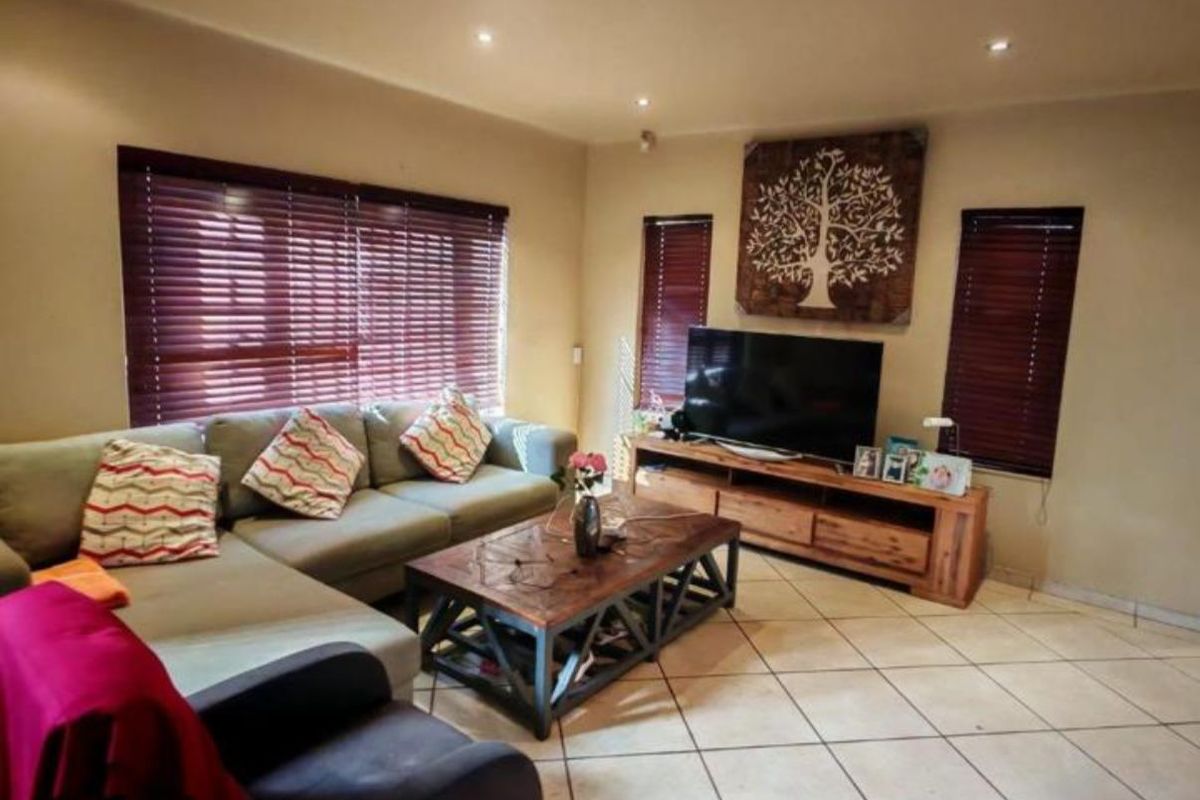 A comfortable living room featuring tiled flooring, recessed downlighting, and venetian blinds, providing a functional and well-lit space for relaxation.