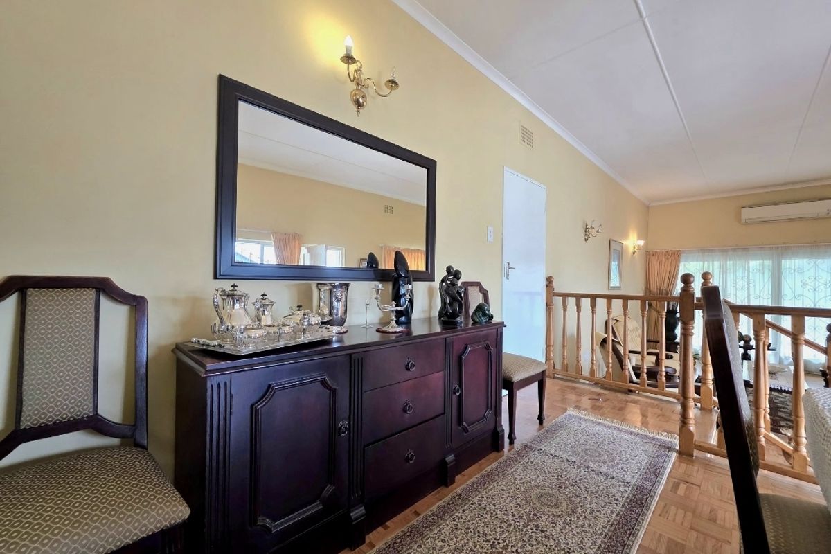 A living area featuring parquet flooring, wall sconces, and a wooden balustrade overlooking the lower level, equipped with a split-system air conditioner.