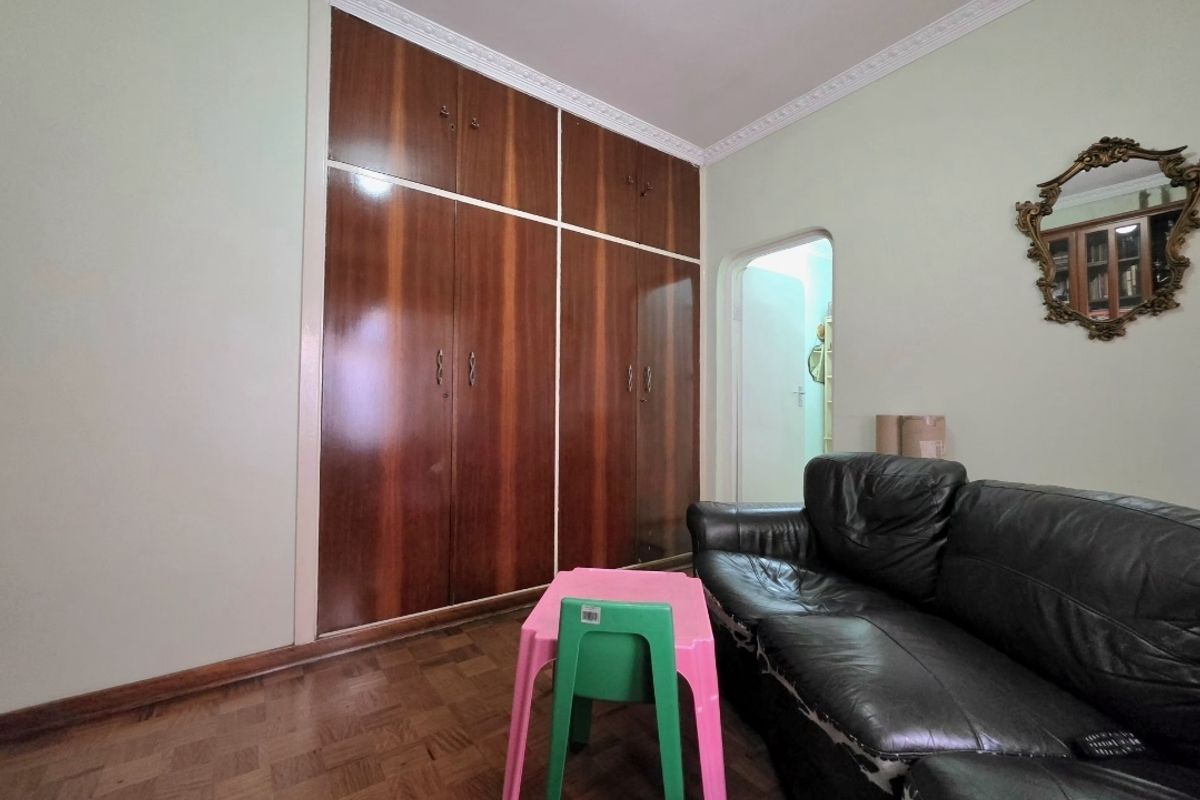 Bedroom featuring classic parquet flooring, decorative ceiling cornice, and extensive built-in wooden cabinetry providing ample storage space.