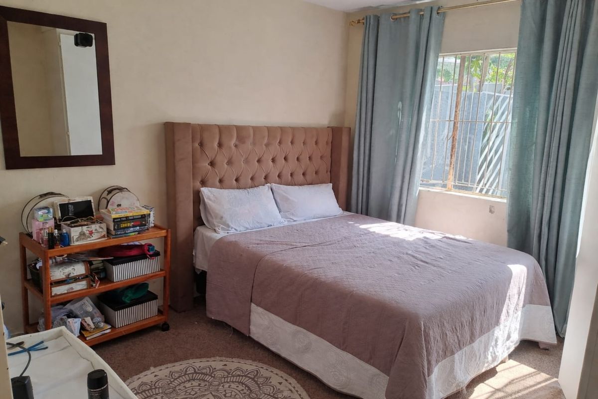 A standard bedroom featuring a window with security bars and neutral wall finishes, providing a functional space for rest.