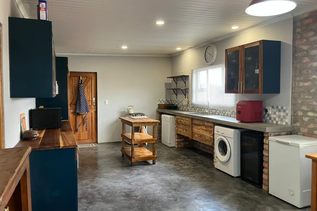 Spacious kitchen featuring polished concrete floors, exposed brick accents, custom cabinetry with concrete countertops, and integrated laundry appliance connections.