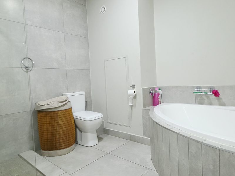 Modern bathroom featuring a built-in bathtub, separate shower with glass screen, and neutral large-format wall and floor tiling.