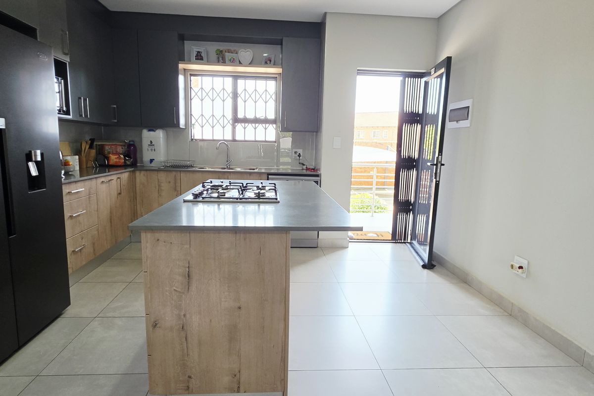 Modern kitchen featuring a central island with a gas hob, ample built-in cabinetry, and direct access to the exterior.