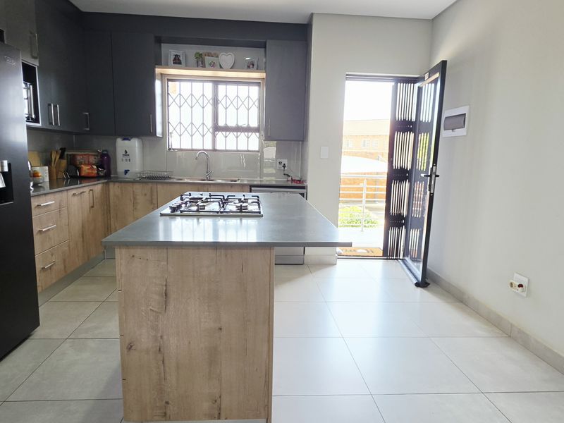 Modern kitchen featuring a central island with a gas hob, ample built-in cabinetry, and direct access to the exterior.