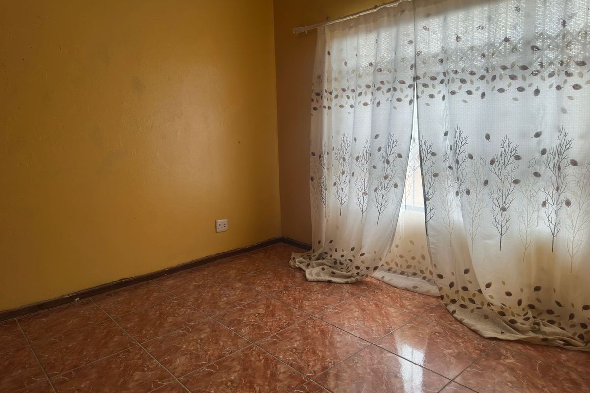 A vacant bedroom featuring tiled flooring and yellow painted walls, ready for personalization.