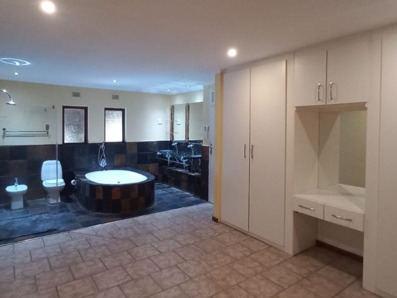 Spacious bathroom featuring a sunken bathtub, separate shower, bidet, toilet, and extensive built-in cabinetry with a vanity area.