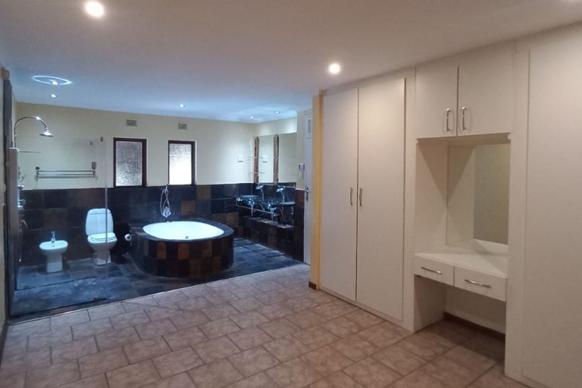 Spacious bathroom featuring a sunken bathtub, separate shower, bidet, toilet, and extensive built-in cabinetry with a vanity area.