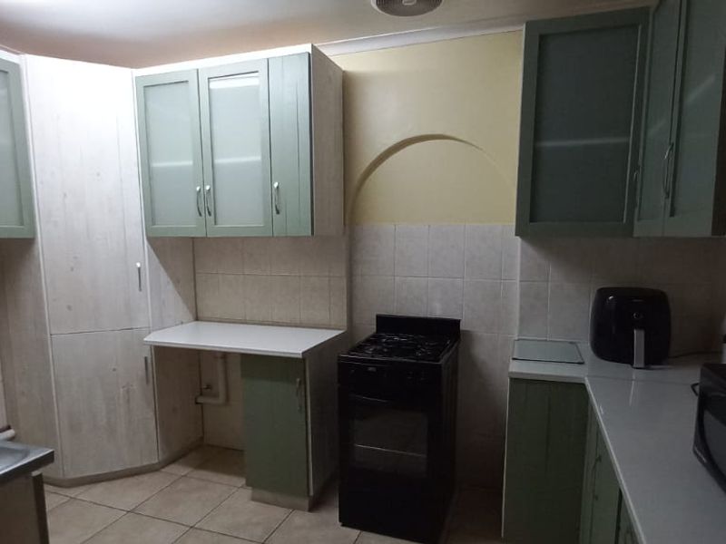 A functional kitchen featuring built-in cabinetry, tiled splashbacks, a double sink, and a freestanding stove, offering a practical layout with potential for modern updates.