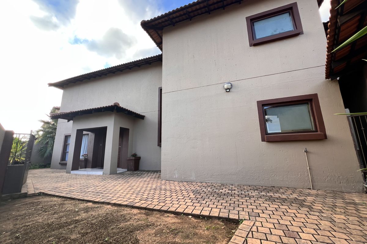 Rear exterior view of the house featuring a paved patio area, tiled roof, and external wall finishes.