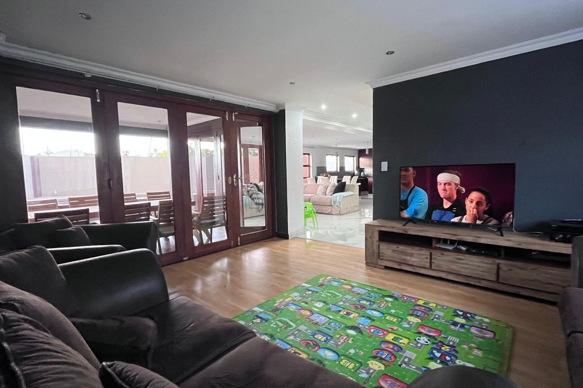 Spacious living room featuring laminate flooring, recessed downlights, and large wooden folding doors providing access to the outdoor patio area.