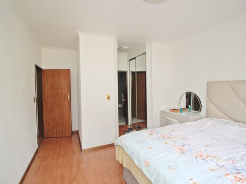 A bedroom featuring laminate flooring, coved ceilings, and a built-in mirrored wardrobe, providing functional storage and a neutral base.