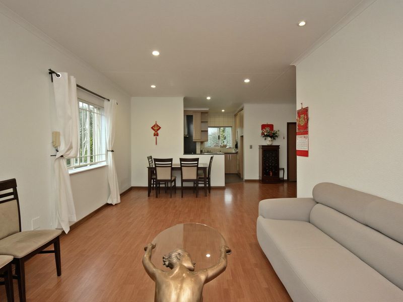 Open-plan living and dining area featuring laminate flooring, recessed lighting, and a functional kitchen layout with built-in cabinetry.
