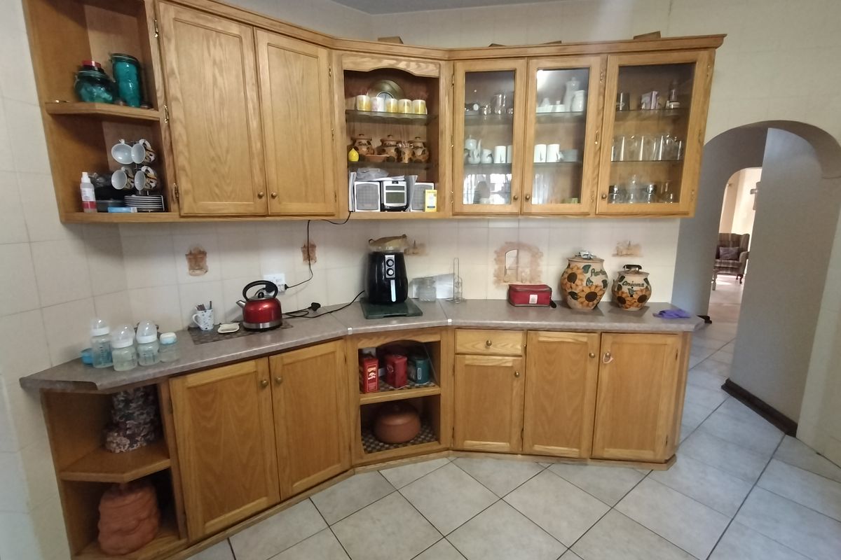 A traditional kitchen featuring timber cabinetry, laminate countertops, and ceramic tiling throughout, offering a functional layout with ample storage space.