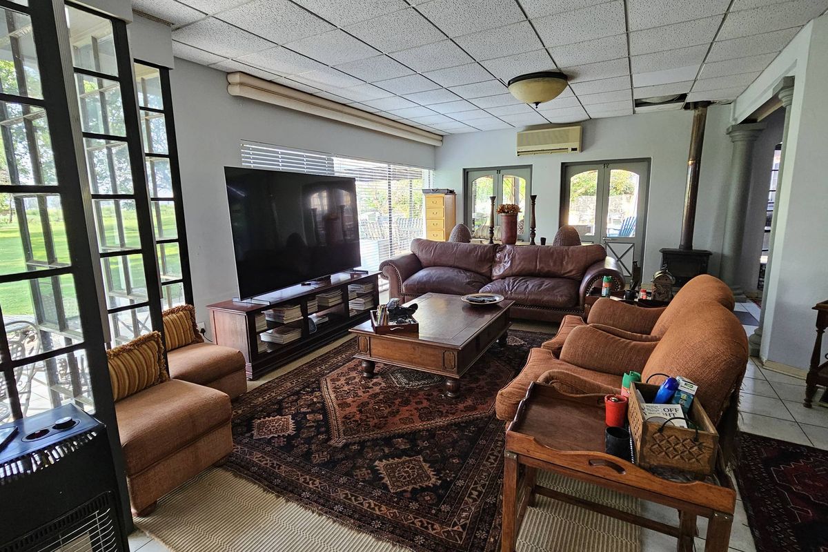 Spacious living room featuring a wood-burning stove, split-system air conditioning, and large windows with garden views, offering a comfortable and functional layout.