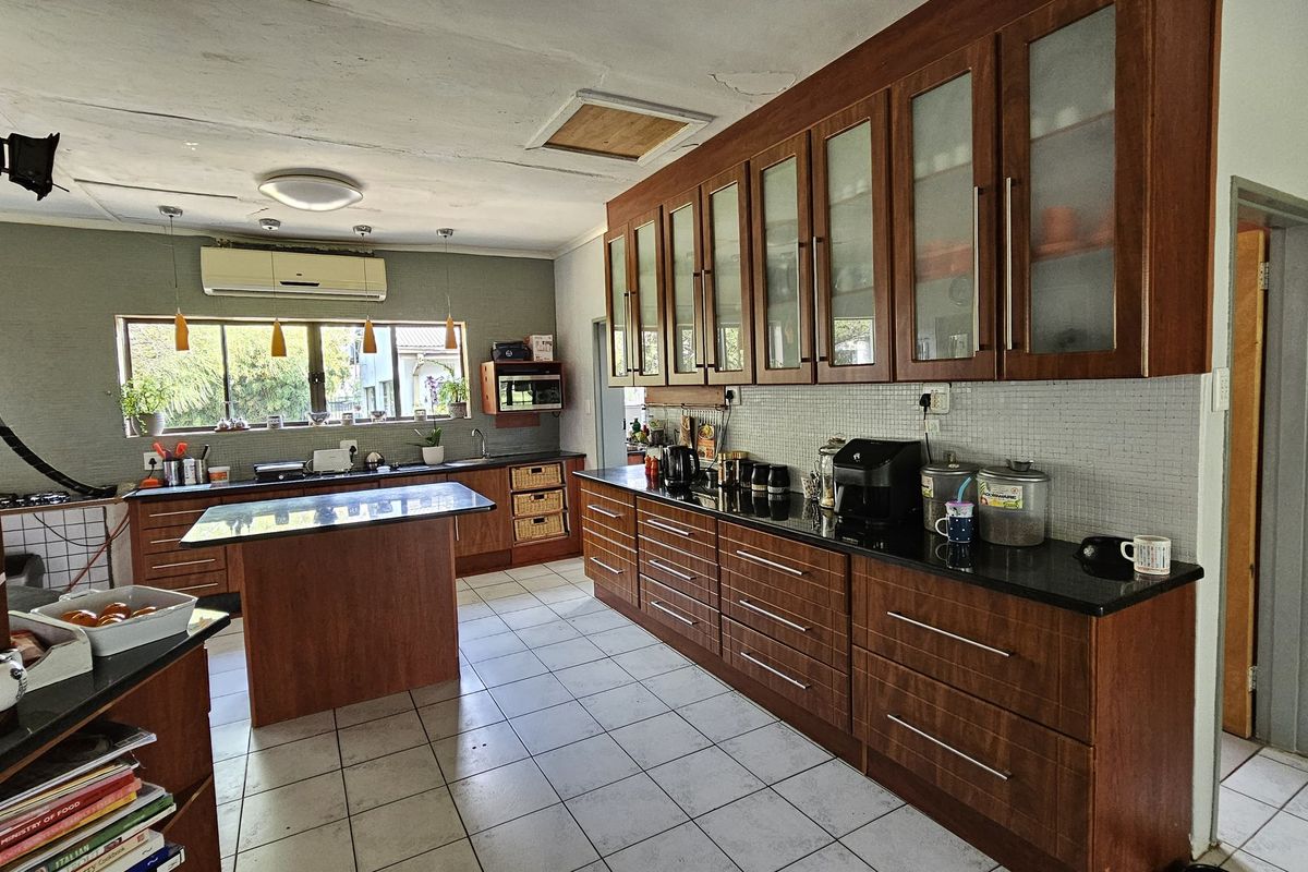 Spacious kitchen featuring extensive wood-finish cabinetry, granite countertops, a central island, and tiled flooring, offering ample storage and workspace for a farm property.
