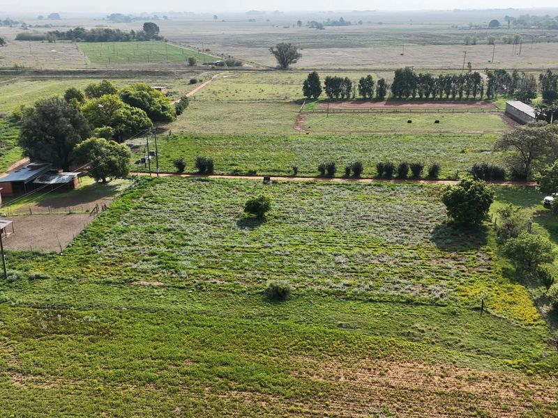 Aerial view of a large farm property featuring open fields, established trees, and various outbuildings.