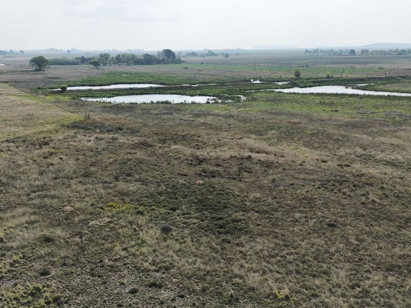 An aerial view of the expansive farm property featuring natural wetlands and open grazing pasture land.