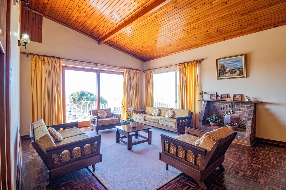 Spacious living room featuring a vaulted timber-clad ceiling, classic parquet flooring, and a traditional brick fireplace, with large sliding doors providing natural light.