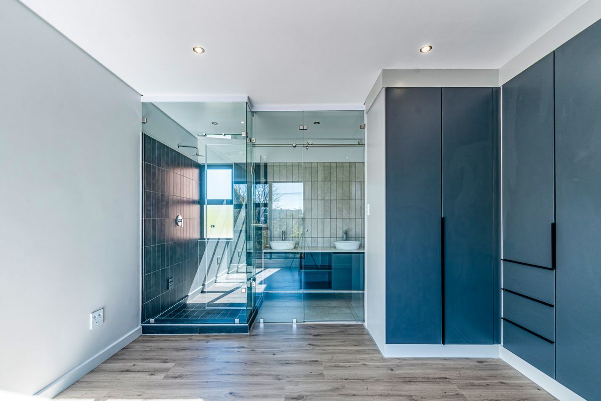 Modern bathroom featuring a glass-enclosed shower, dual vanity with contemporary fixtures, and sleek built-in cabinetry, finished with high-quality tiling and recessed lighting.