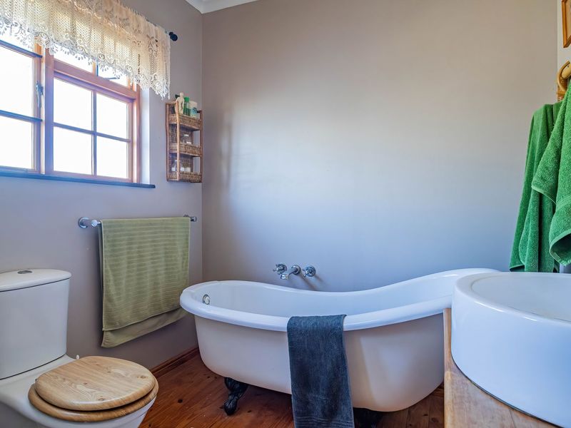 A charming bathroom featuring a classic clawfoot bathtub, wall-mounted faucet, vessel sink, and warm timber flooring, creating a cozy and character-filled space.