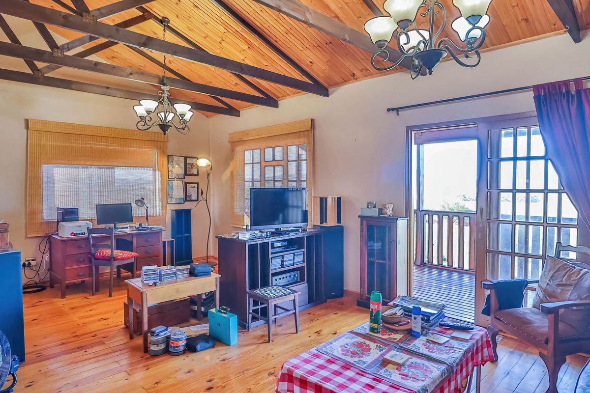 Spacious living room featuring exposed timber ceiling beams, warm timber flooring, and a sliding glass door providing access to an outdoor balcony.