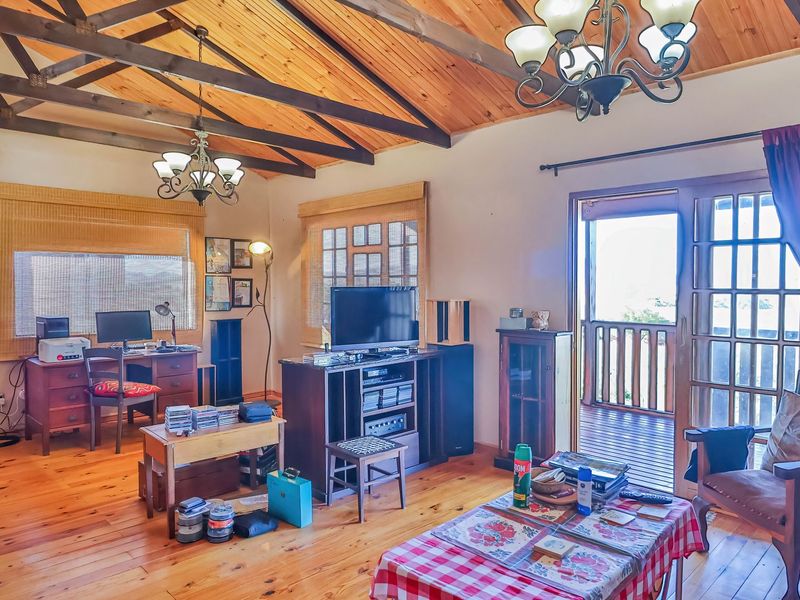 Spacious living room featuring exposed timber ceiling beams, warm timber flooring, and a sliding glass door providing access to an outdoor balcony.