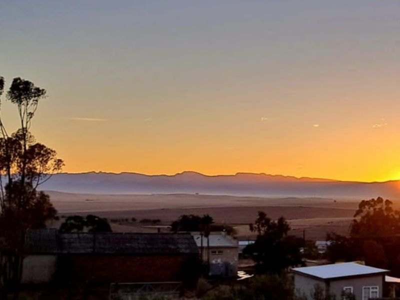 A scenic sunset view overlooking the surrounding landscape and distant mountain range, showcasing the property's elevated position and natural outlook.
