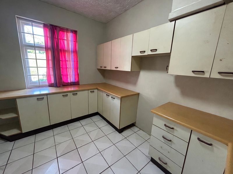 A functional kitchen space featuring ample built-in cabinetry, laminate countertops, and tiled flooring, ready for a modern update.
