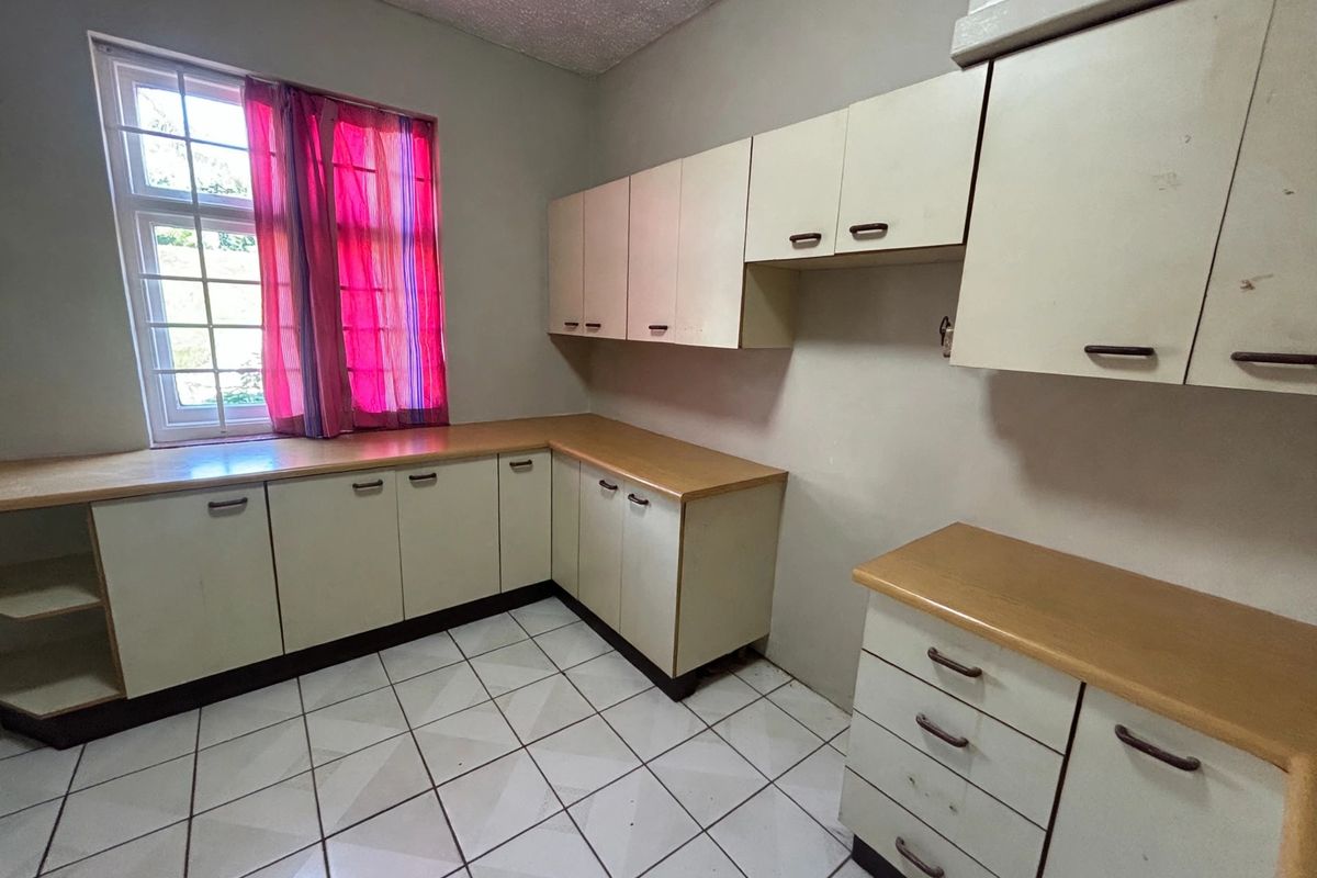 A functional kitchen space featuring ample built-in cabinetry, laminate countertops, and tiled flooring, ready for a modern update.