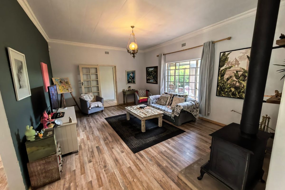 Spacious living room featuring wood-look laminate flooring, a prominent wood-burning stove on a hearth, and classic cornice detailing.