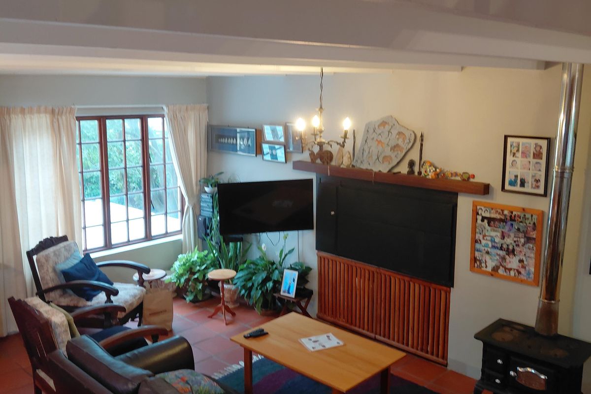 A cozy living room featuring terracotta floor tiles, a wood-burning stove, and a timber mantelpiece, offering a warm and traditional atmosphere.
