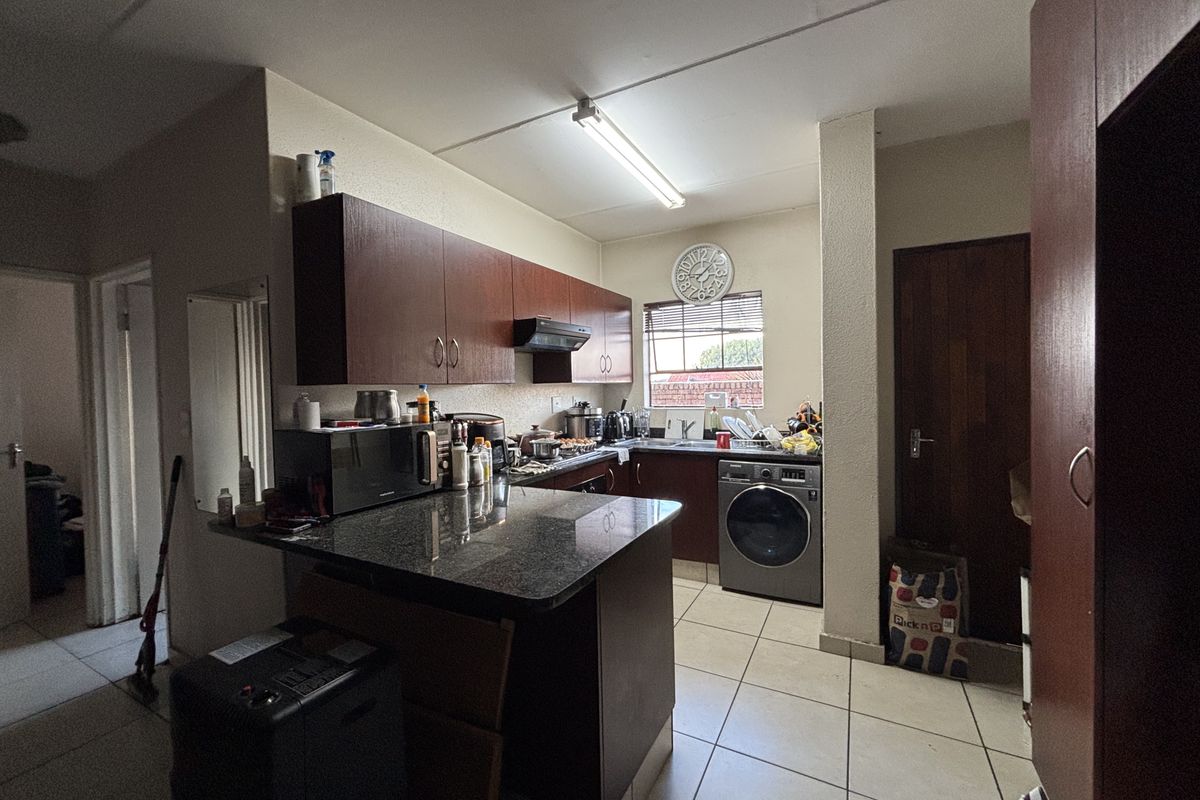 A functional kitchen featuring dark laminate cabinetry, granite countertops, and integrated laundry facilities with ceramic floor tiling.