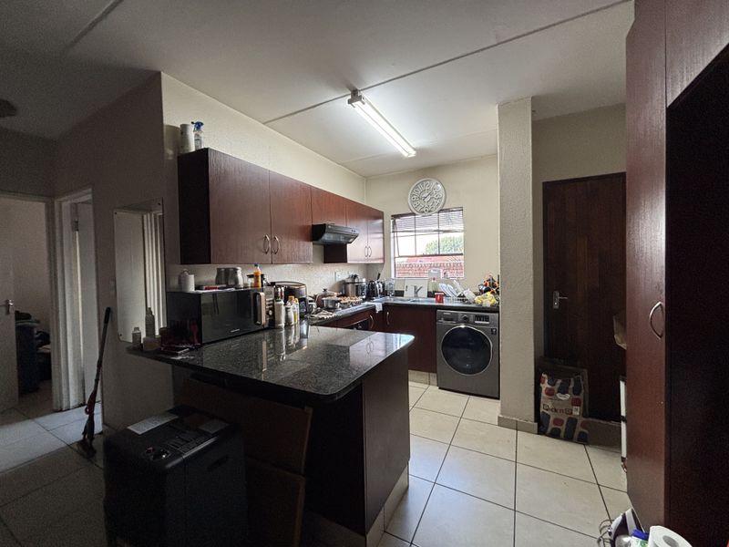 A functional kitchen featuring dark laminate cabinetry, granite countertops, and integrated laundry facilities with ceramic floor tiling.
